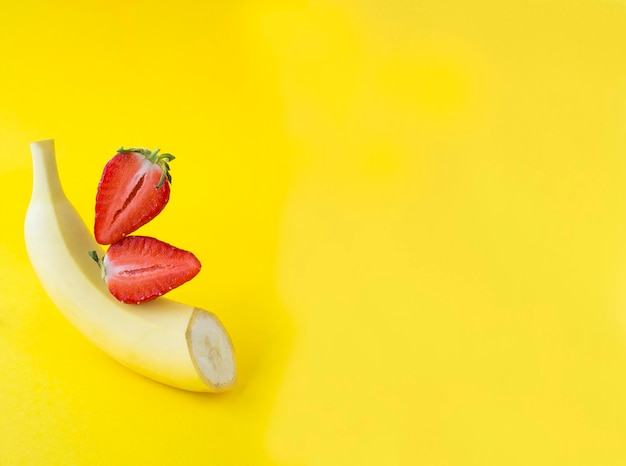 Piramide van banaan en aardbei in balans op de gele achtergrond Kopieer ruimte Close-up