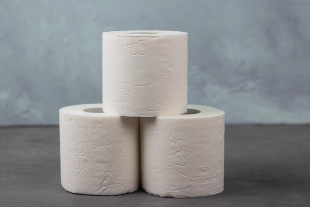 Piramide van drie rollen toiletpapier op een grijze achtergrond