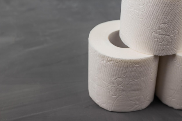 Piramide van drie rollen toiletpapier op een grijze achtergrond