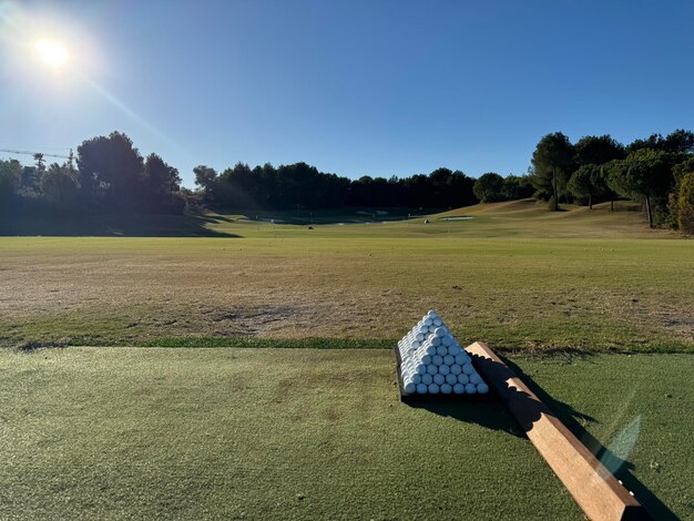 Foto piramide van golfballen in driving range met een mooie golfbaan op de achtergrond