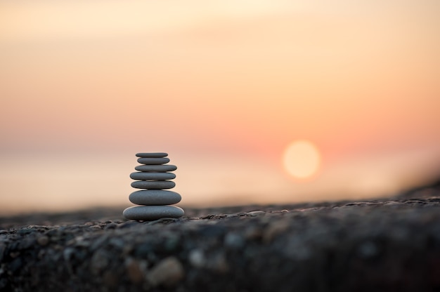 Foto piramide van stenen door de zee bij zonsondergang. evenwichtige zen-stenen.