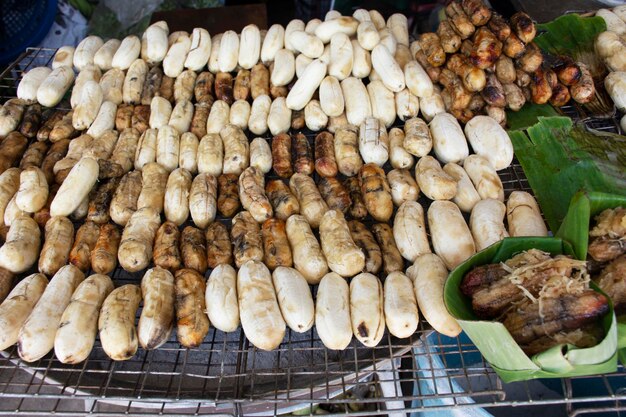 Pisang Awak of gecultiveerde bananen gegrild geroosterd met vachthoning op lokale kolenkachel te koop Thaise mensen en buitenlandse reizigers op antieke vintage retro markt baan madua in Nong Bua Lamphu Thailand