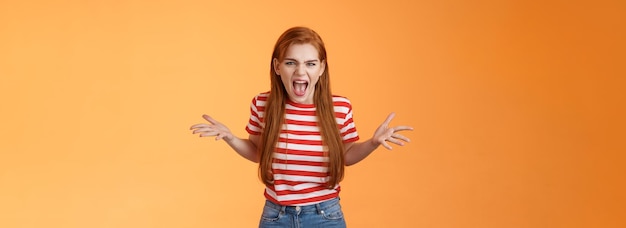 Photo pissed angry and annoyed redhead female arguing yelling with hatred and anger spread hands sideways