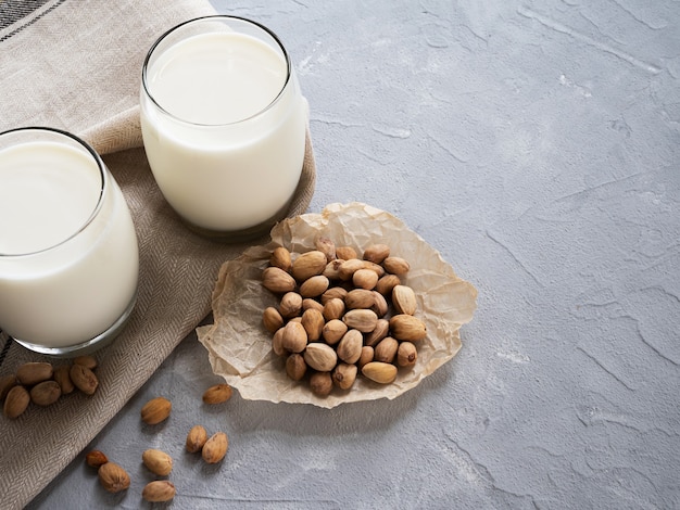 Pistachemelk in een glas Beker en pistachenoten op een grijze concrete achtergrond.