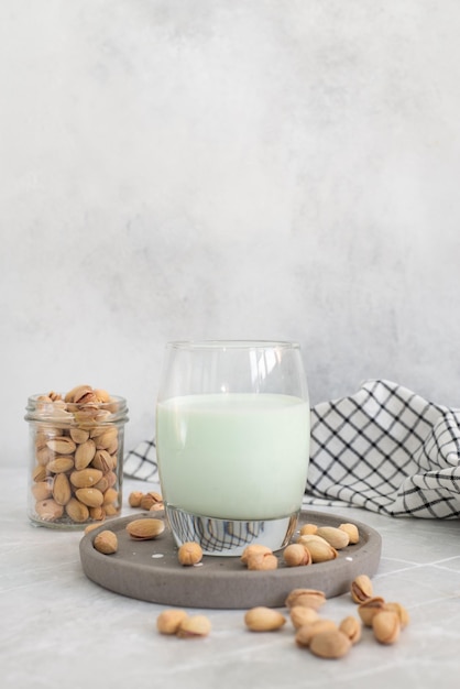 Pistachemelk in een glas met pistachenoten op een grijze achtergrond