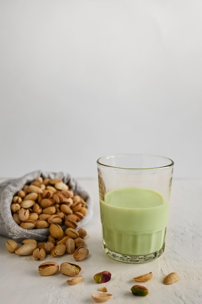 Foto pistachemelk in het glas op de witte achtergrond deze melk is een geweldige bron van antioxidanten, fytosterolen en gezonde hartvetten