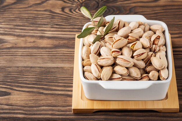 Pistachenoten en bladeren in een witte plaat op een houten standaard en tafel