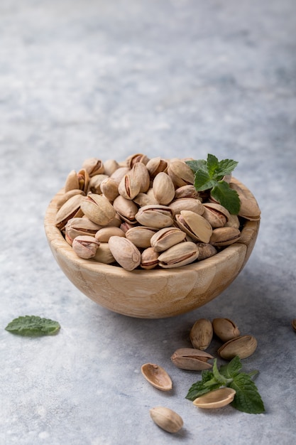 Pistachenoten in een bruine kom op een betonnen achtergrond