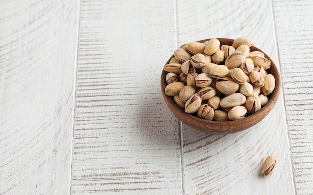 Pistachenoten in een kom op een lichte houten tafel