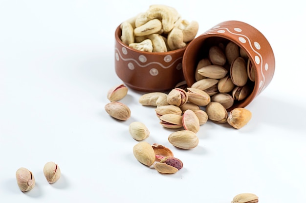 Pistachio and Cashew Nuts in clay pots on white