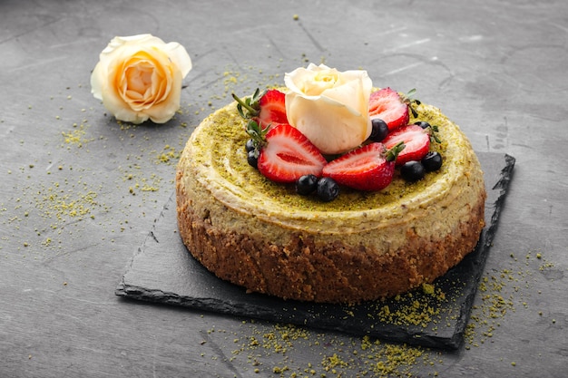 Pistachio cheesecake garnished with strawberries and rose