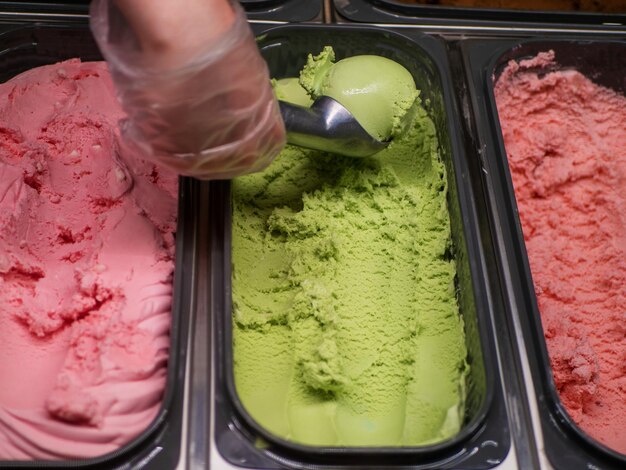 Foto pallina per gelato al pistacchio per servire il gelato tre tipi di gelato in vaschette di acciaio