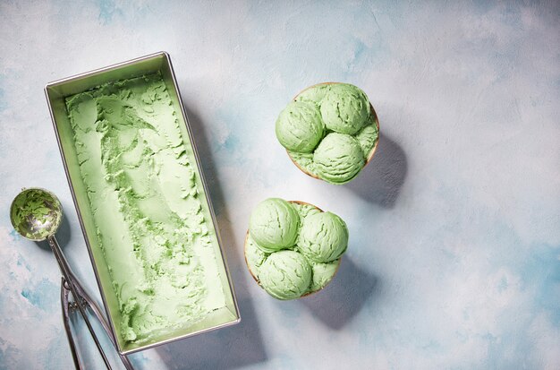 Pistachio ice cream scooped out of container, top view.