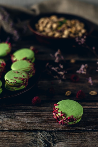 pistachio macarons on wooden background with raspberries