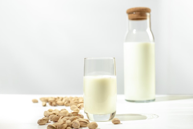 Pistachio milk the glass next to bottle of milk and pistachios