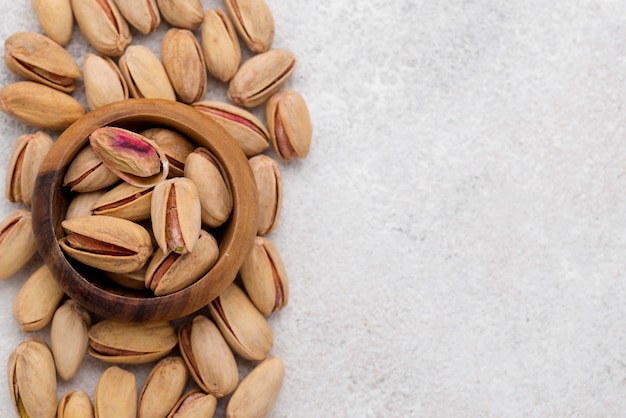 Pistachio nuts and bowl on marble table copy space