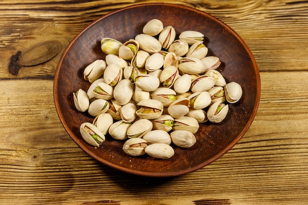 Pistachio nuts in ceramic plate on a wooden table