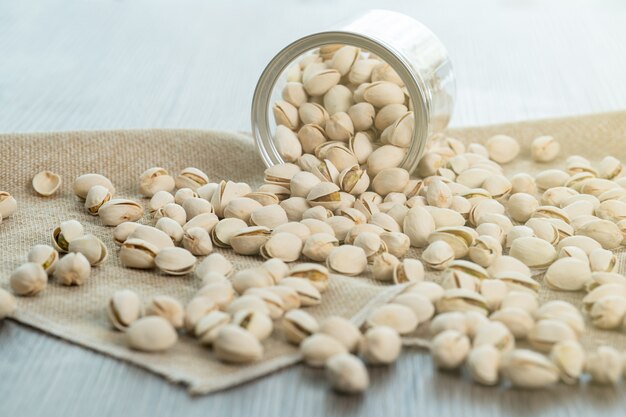 Pistachio nuts in transparent glass jar on a wooden table. Healthy food high protein.