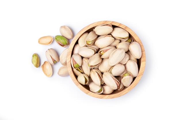 Pistachio nuts in wooden bowl isolated on white background Top view