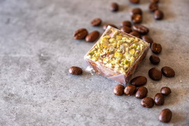 灰色の背景にコーヒー豆とピスタチオのお菓子