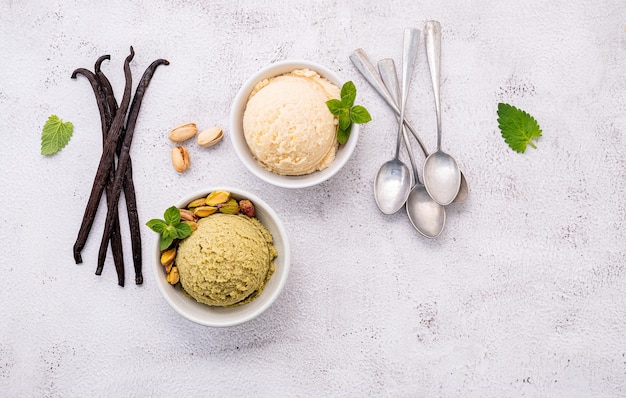 Pistachio and vanilla ice cream in bowl  with mixed nuts setup on white stone background