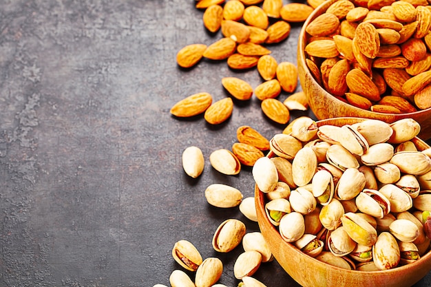 Pistachios and almonds in wooden bowls standing on rustic