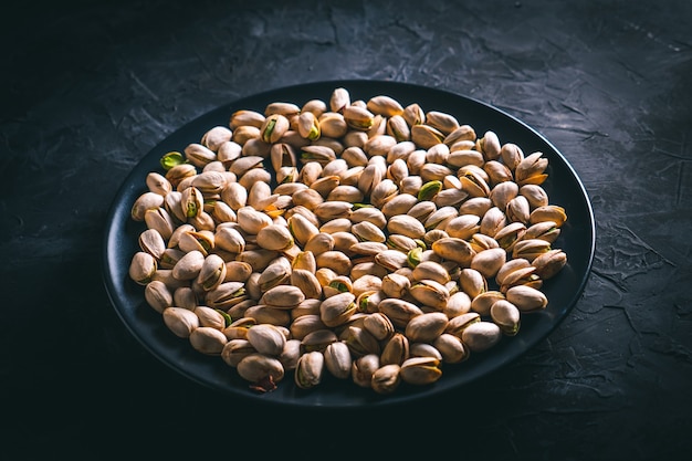 Pistachios in a black plate on a dark table Ready to eat nuts Energy food