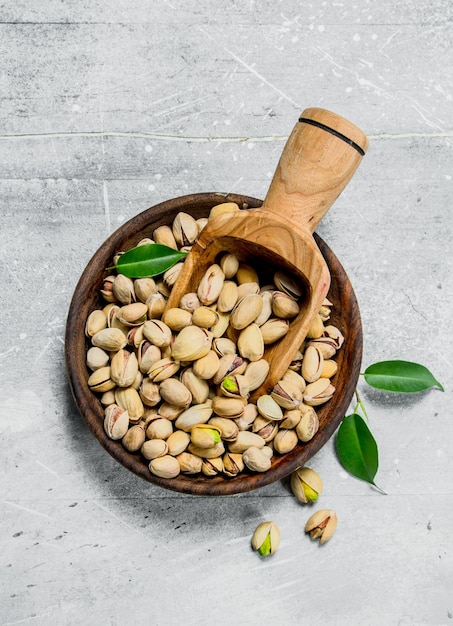 Pistachios in bowl with wooden scoop