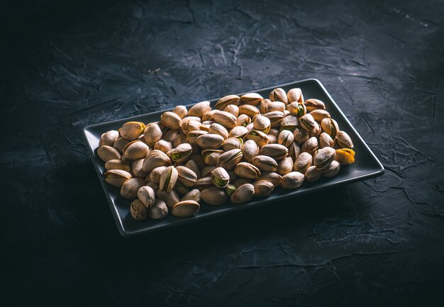 Pistachios in a gray rectangular plate on a dark table