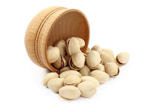 Pistachios pouring out of wooden bowl