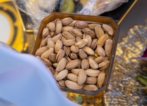 Pistachios in a small plate on a wooden table as a background