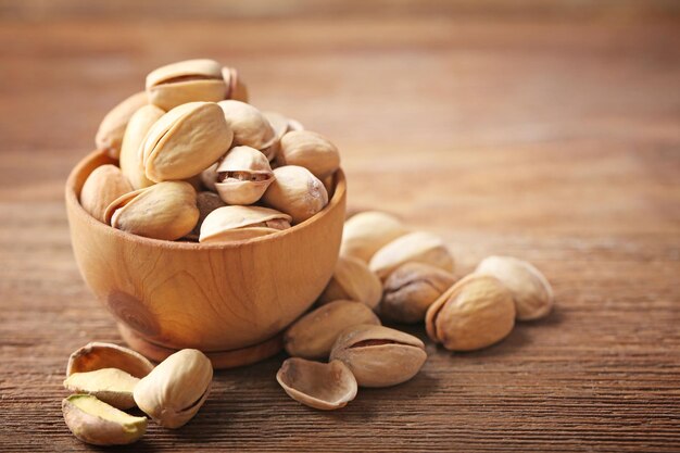 Pistachios in the wooden bowl on the table closeup