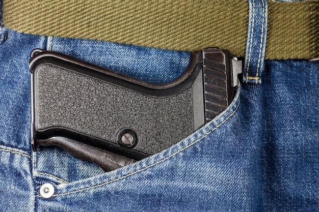 Pistol in the pocket of jeans.