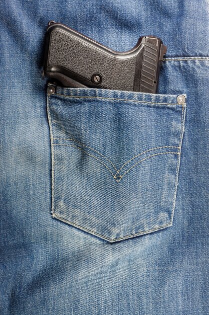 Pistol in the pocket of jeans.