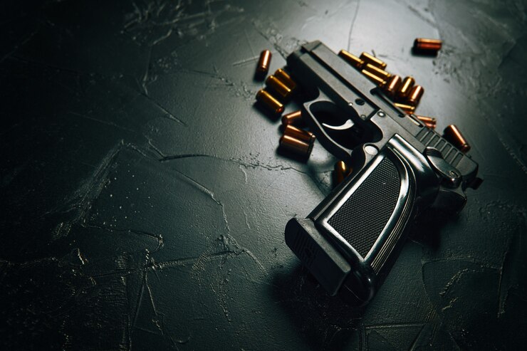 Pistol with bullets on concrete table black gun and brass cartridges firearms closeup weapon of crim...