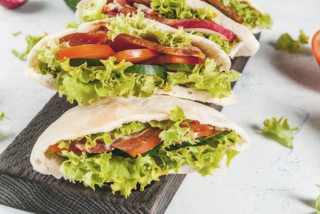 Pita bread sandwich with fresh vegetables on a light concrete table