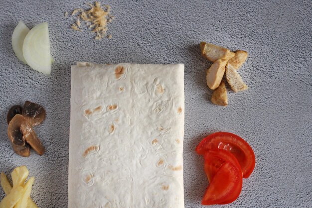 Pita bread with potatoes tomato mushrooms onions cheese meat on a gray background top view