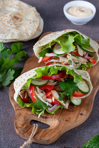 Pita gevuld met kip, paprika, komkommer en sla op een houten bord. Midden-Oosterse keuken. Verticaal formaat