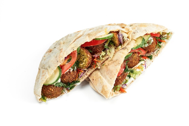 Photo pita with falafel, fresh vegetables and white sauce on a white plate. photo for the menu. isolated