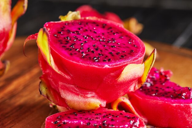 Pitahaya's In stukken gesneden op een houten standaard op een zwarte houten