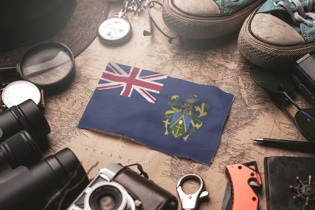 Pitcairn Islands Flag Between Traveler's Accessories on Old Vintage Map. Tourist Destination Concept.