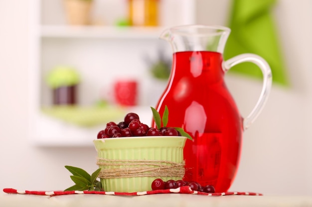 Pitcher and glass of cranberry juice with red cranberries on table