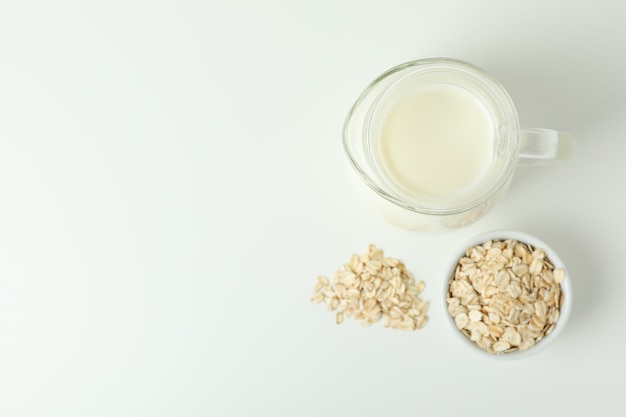 Pitcher of milk and cereals on white background