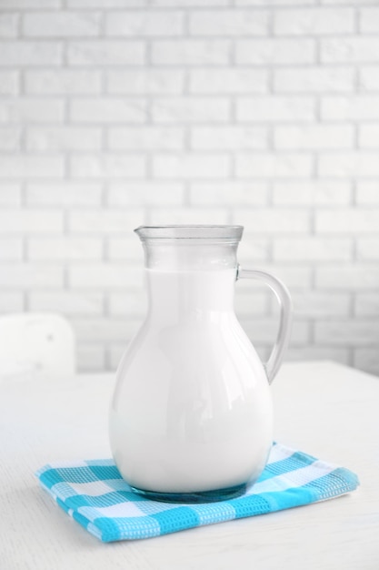 Фото Кувшин молока на деревянном столе на фоне кирпичной стены