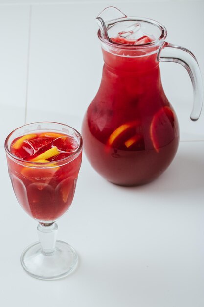 A pitcher of red raspberry punch sits next to a pitcher of red raspberry lemonade.