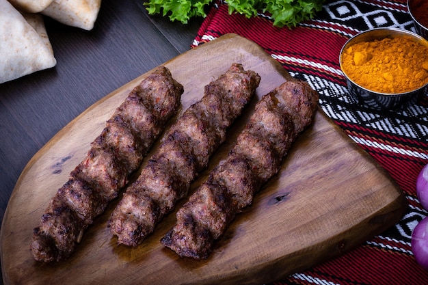 Pittig vlees seekh Kebab geserveerd in houten plank geïsoleerd op tafelblad weergave van Arabisch eten