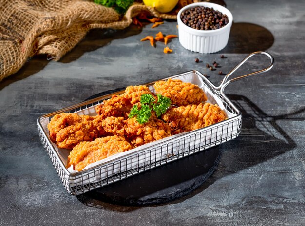 Pittige crispy wings met zwarte peper in het zijaanzicht van de friteuse op een donkere achtergrond fastfood