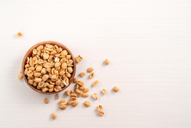 Pittige gearomatiseerde pinda kernel in een kom op witte tafel achtergrond