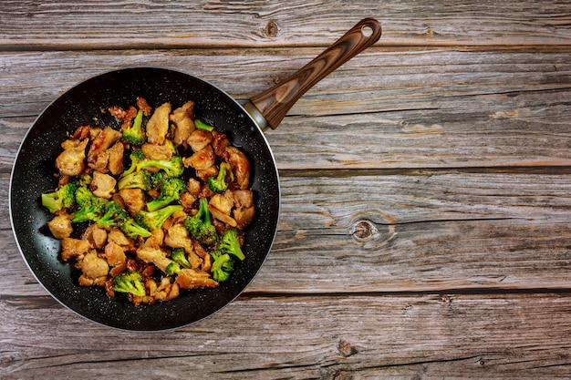 Pittige kip teriyaki met broccoli in pan op houten rustieke tafel.