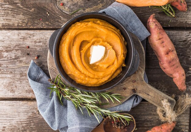 Pittige puree van zoete aardappel of zoete aardappelpuree met rozemarijn in een pan op een tafel. bovenaanzicht van boven